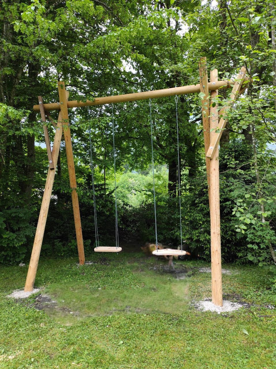 Selbst gebaute Holzschaukel aus Rundhölzern in einem Garten.